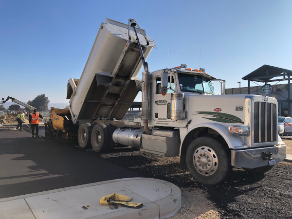 asphalt being dumped from truck into paver